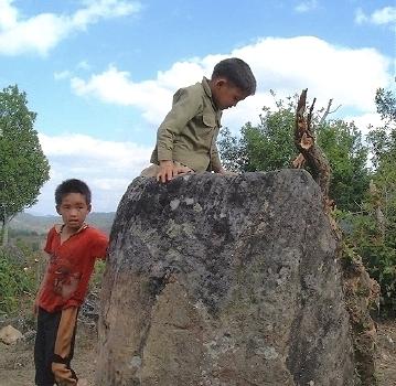  Two local boys, one climbing a fairly large stone 'jar' 