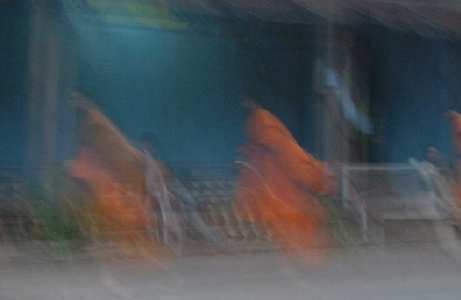 FASTER THAN A SPEEDING BULLET!  Our digital camera couldn't quite cope with the low light of this early morning (6:00? 6:30?) shot, and of course we didn't want to be obnoxious and use our flash.  But that all worked to our advantage, really, as it gave us this surreal image of monks walking down a main road in town, gratefully accepting small clumps of rice from people at various points along the way.
