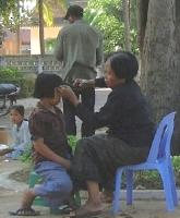 Child getting a haircut on the street, probably from grandma [Siem Reap, Cambodia]