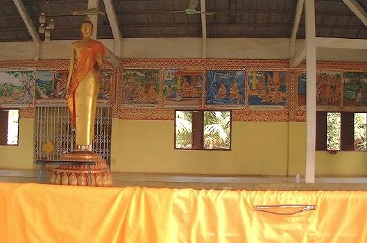 Wat Phonxai (Vientiane): an open-air part of the wat, with a standing Buddha statue, and a monk's garment drying off on the railing